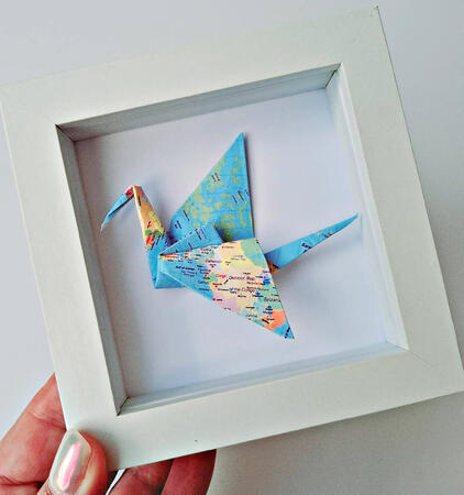 Hand folded origami lucky crane in a mini frame with world map travel theme